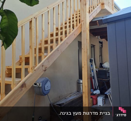 גרם מדרגות עץ ליד קיר עם צינור מים